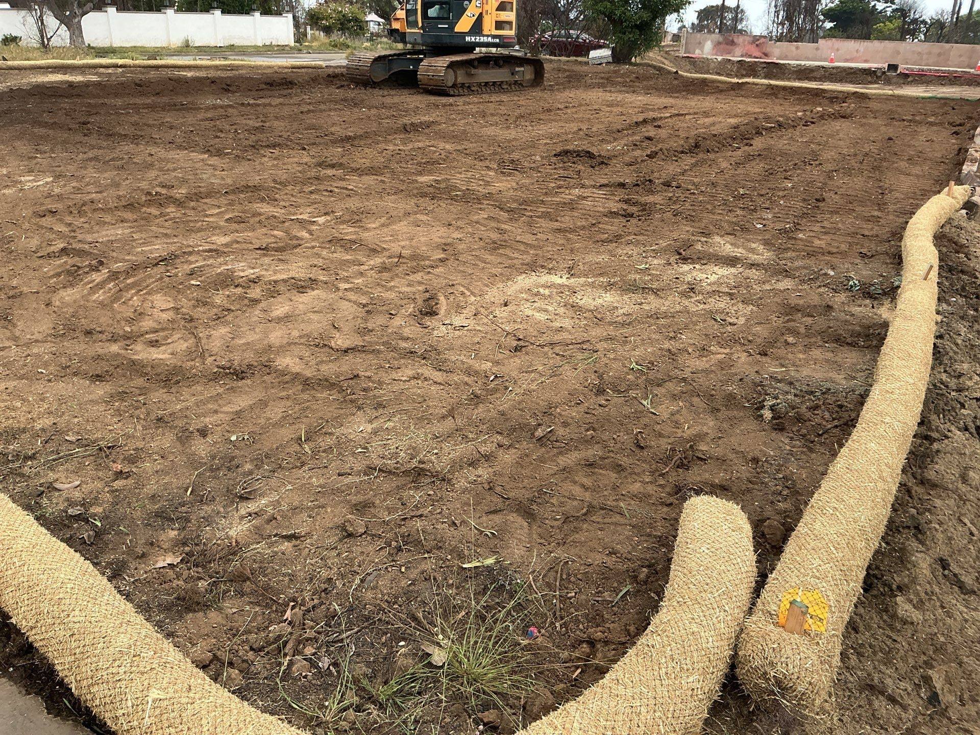 Cleared lot with straw wattles laid along the edge for erosion control