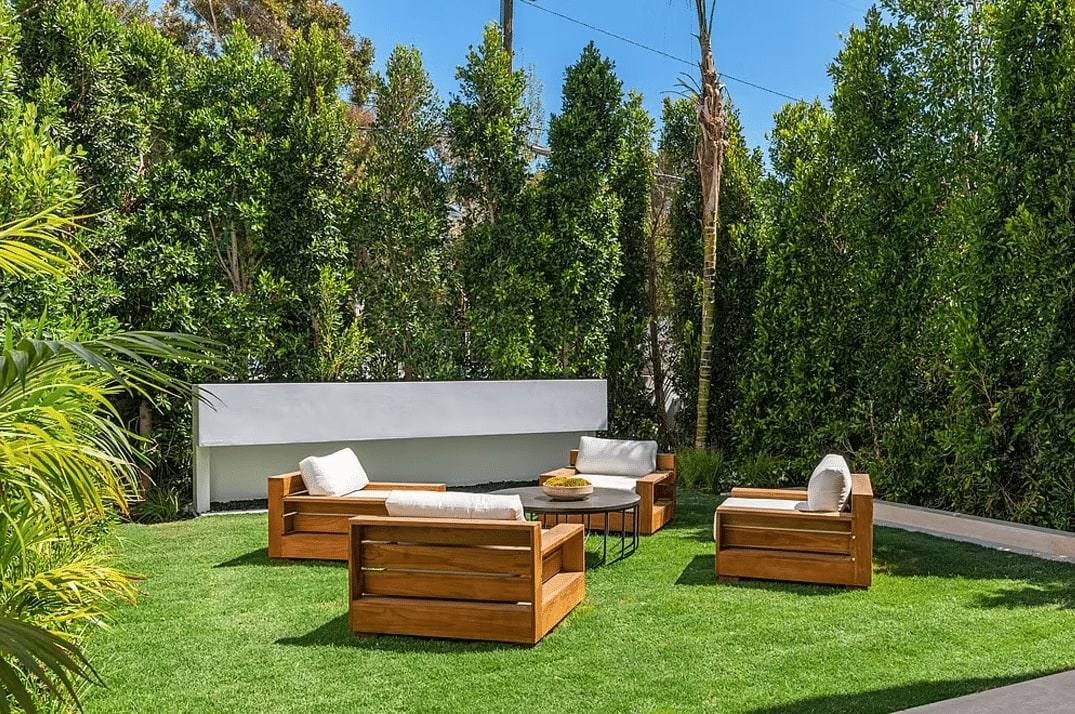 Garden lounge on a lawn framed by tall hedges