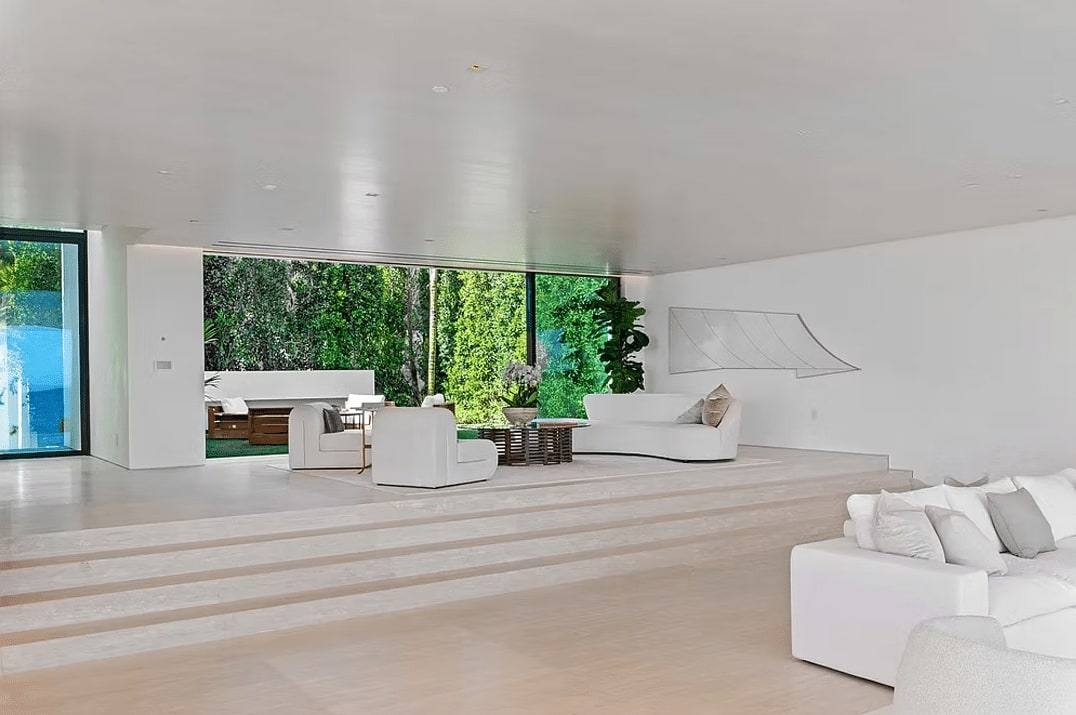 Sunken living room with white sofas and glass walls opening to the garden