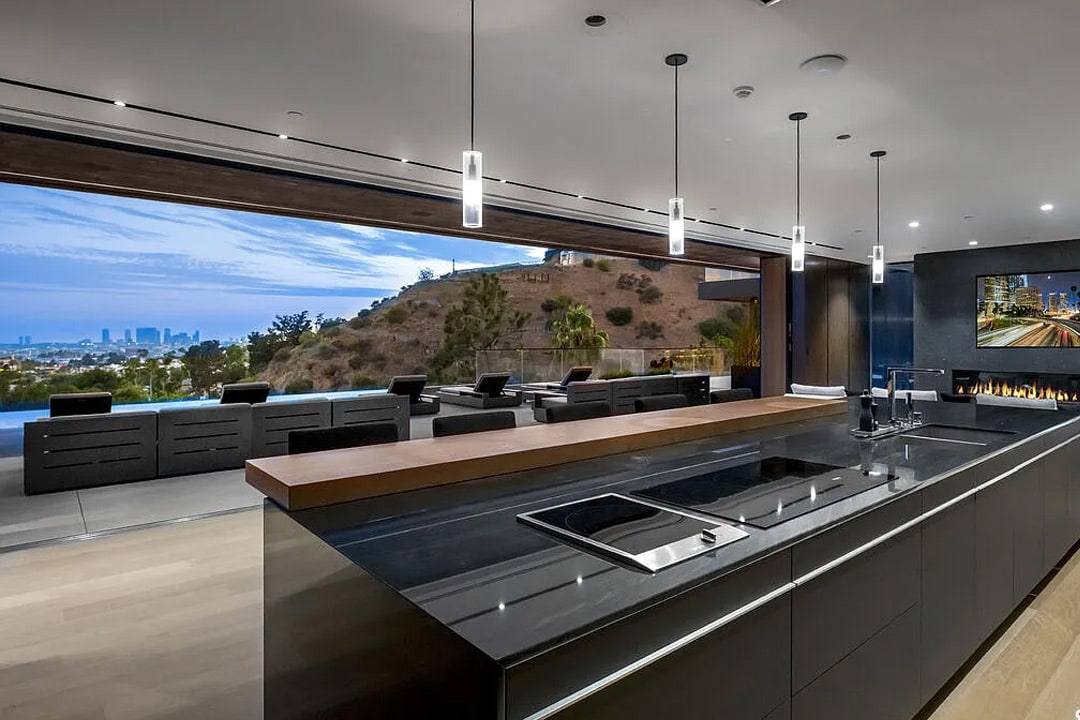 Dark stone kitchen island with wide glass to the hills, in the Hollywood residence