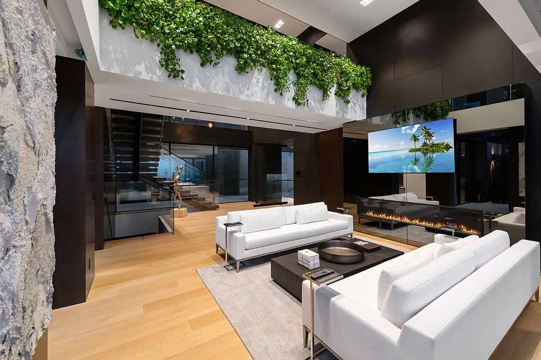 Double-height living room with a planted balcony, a stone wall and a long fireplace