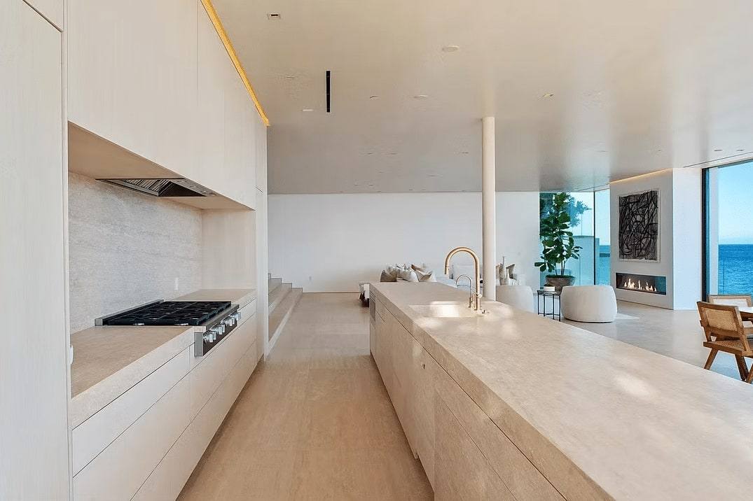Long pale stone kitchen island with a gas range and a window to the beach