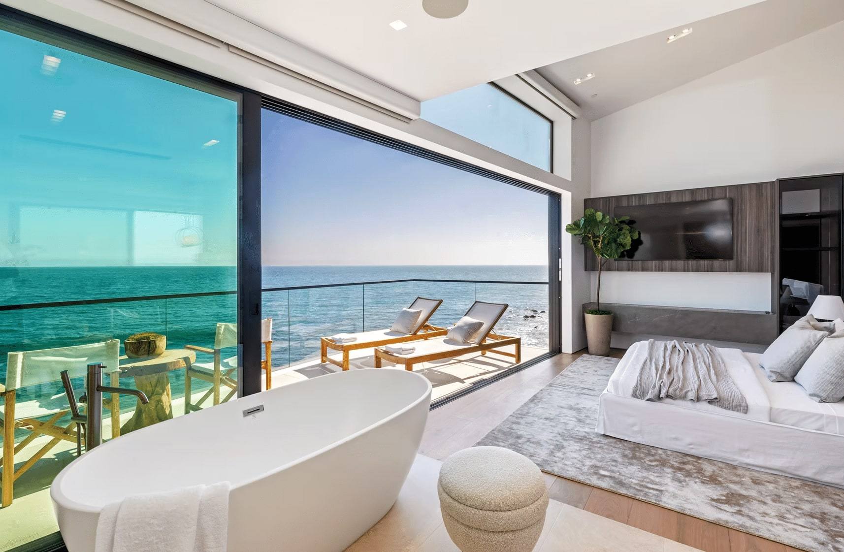 Primary bedroom with a freestanding tub and floor-to-ceiling glass facing the ocean