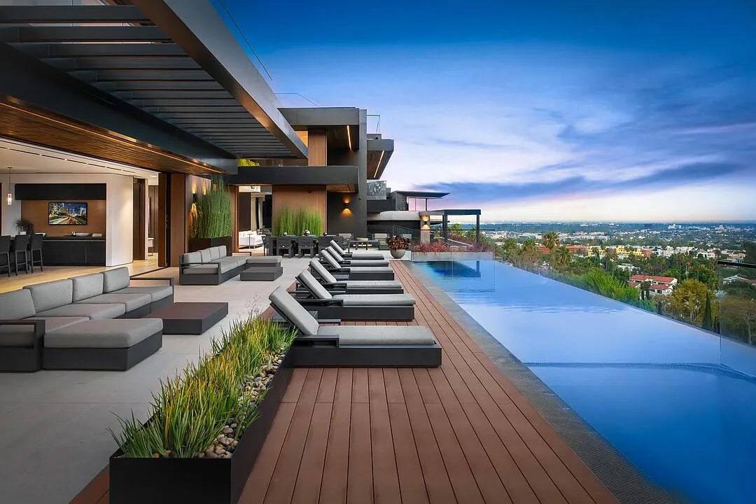 Infinity-edge pool and loungers on a wood deck overlooking Los Angeles
