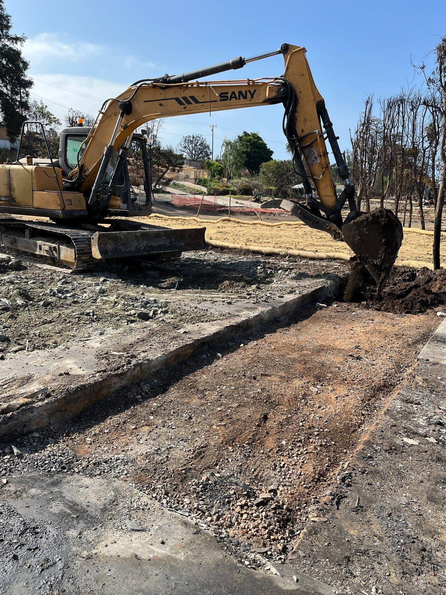 Excavator digging out a burned foundation line