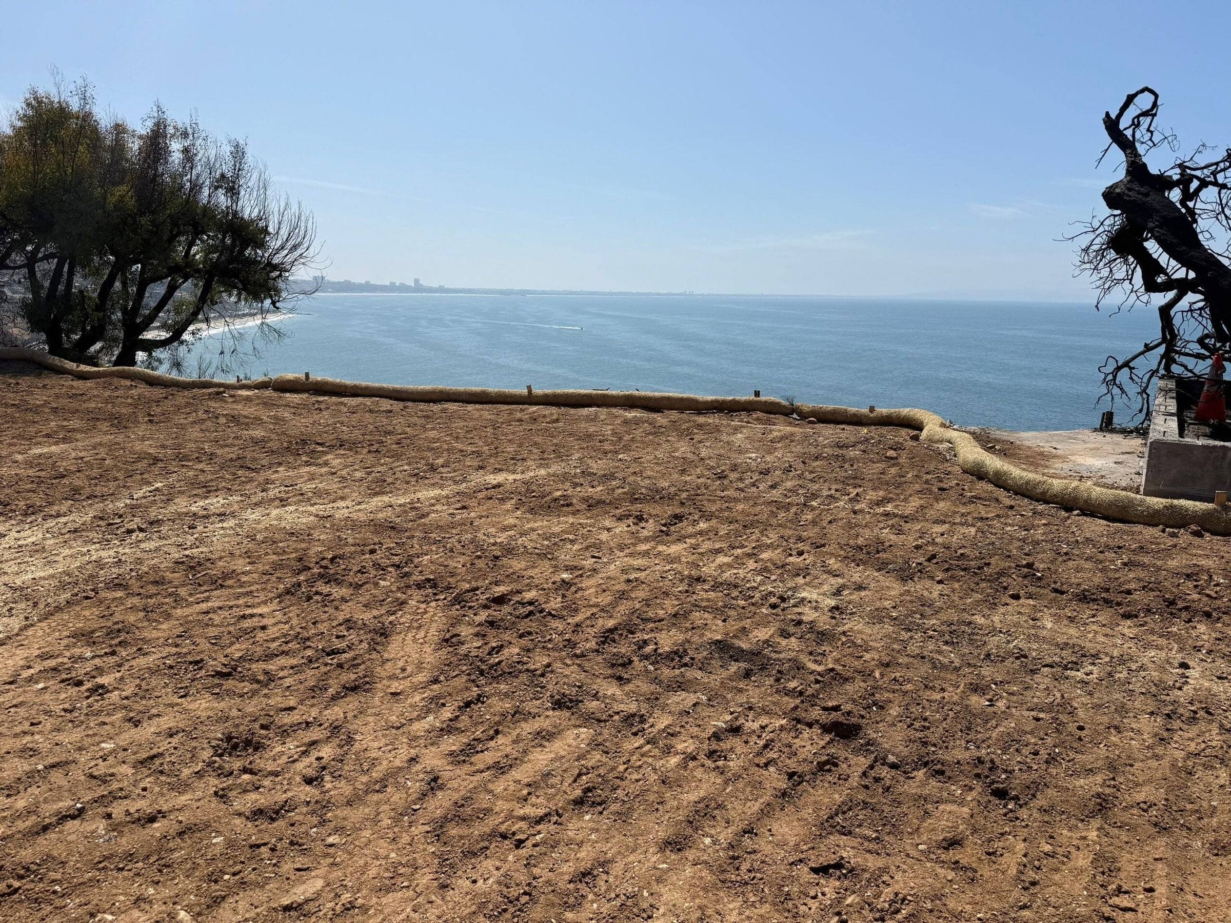 Cleared lot graded flat above the Pacific, with straw wattles along its edge